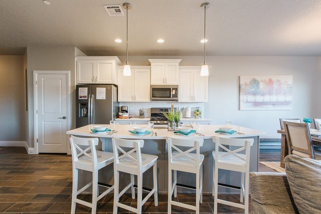Kitchen island with white bar stools and pendant lights