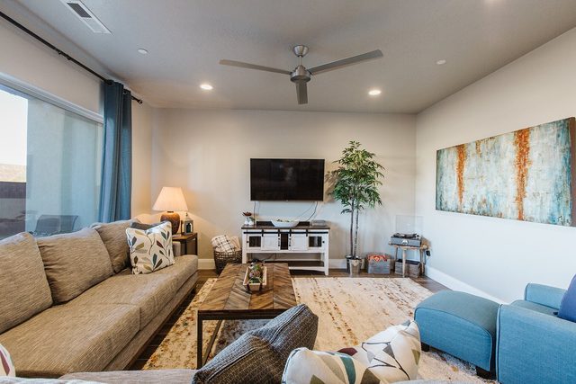 Living room with sectional sofa, wall TV and ceiling fan