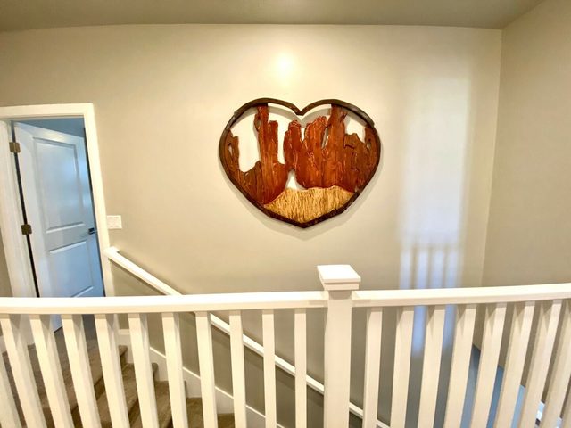 Stair landing with white railing and wood wall art