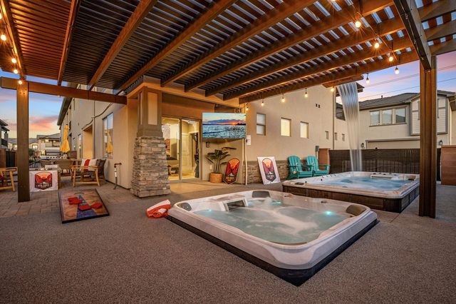 Private hot tub and swim spa under the lit backyard pergola