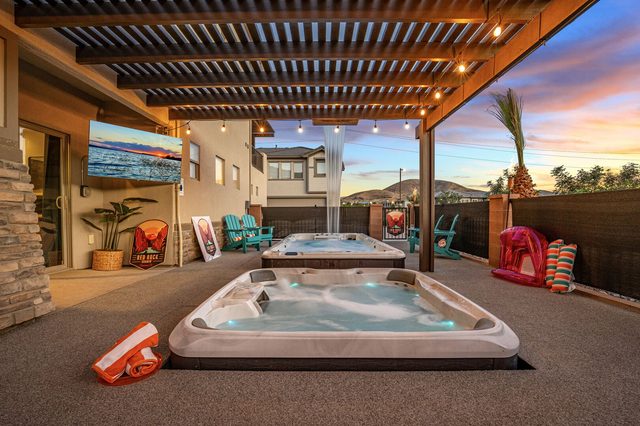 Backyard hot tub under the pergola with outdoor TV at sunset