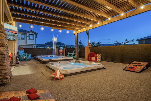 Lit pergola over the hot tub, swim spa and cornhole boards