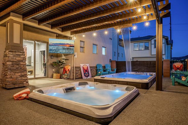 Glowing hot tub and outdoor TV under the pergola at night