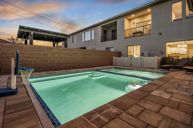 Lit private pool with basketball hoop at twilight