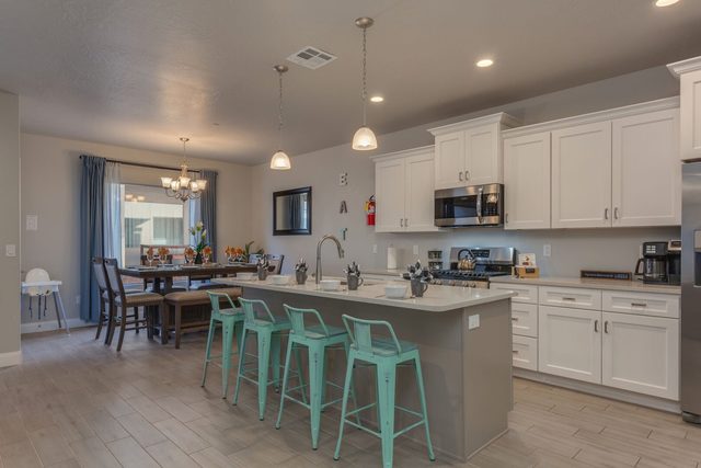 Kitchen island with four teal bar stools and dining area