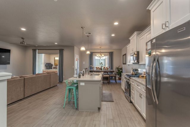 Galley kitchen with stainless refrigerator opening to the living room