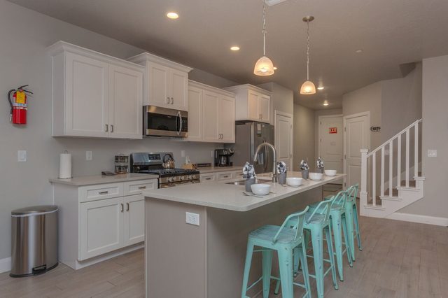 White kitchen with island seating next to the staircase