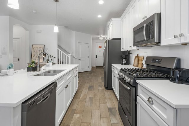 Kitchen sink, dishwasher and gas range with white cabinets